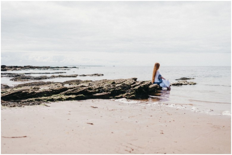 girl sitting on rocks on a beach